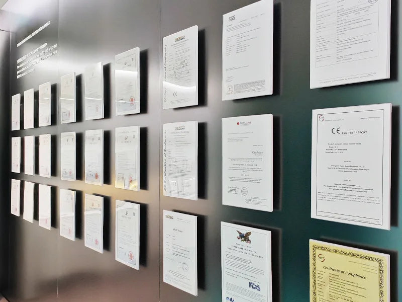 A wall display showing multiple framed certificates and documents mounted in rows against a dark wall.