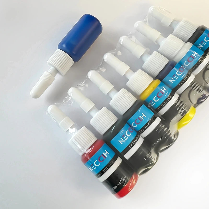 A set of NECCIH tattoo ink bottles in multiple colors including red, black, gray, yellow, and blue, arranged diagonally on a white background with one blue bottle standing upright.